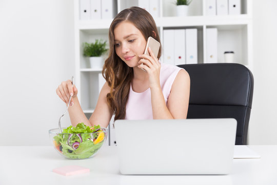 Woman with laptop eating salad