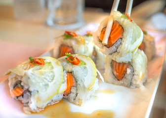 Salmon splash sushi roll selective focus with blurred background