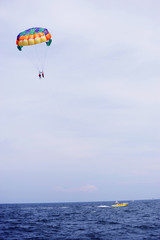 parasailing in summer beach by speed boat, vertical composition