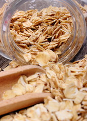 Oat flakes spilling out of jar on wooden background