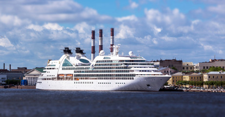 Large white colored ocean ship in Neva river of Saint Petersburg under blue summer cloudy sky