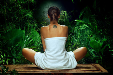 View of nice young woman meditating in spa environment