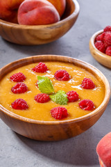 Refreshing cold peach soup garnished with raspberries and mint l