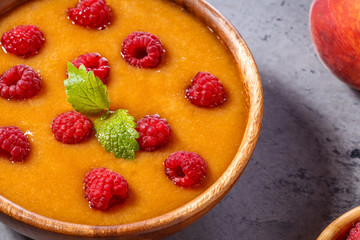 Refreshing cold peach soup garnished with raspberries and mint l