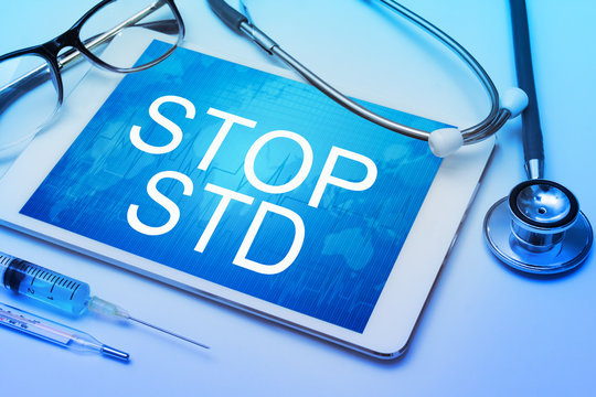 Stop STD (Sexually transmitted diseases) word on tablet screen with medical equipment on background