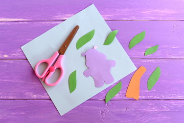 Hippopotamus, leaves, palm tree trunk cut from colorful paper. Set to make a Africa kids card. Stationery on wooden background. Children art project using a colored paper