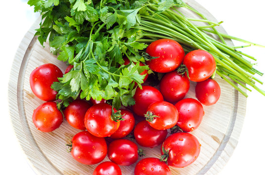 group of red ripe tomatoes and parsley on a wooden board