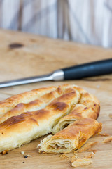 Sliced burek with meat on the wooden board. Rustic food.