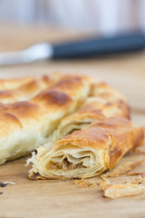 Sliced burek with meat on the wooden board. Rustic food.