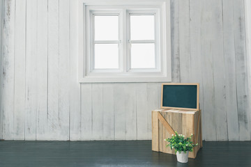 white wooden wall and window background with blackboard, pots and crate at home in the room
