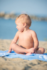 Fototapeta na wymiar Baby playing with toys on the sandy beach near the sea. Cute little kid in sand on tropical beach. Ocean coast.