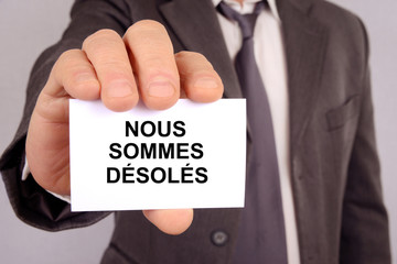Homme tendant une carte avec nous sommes désolés écrit dessus 
