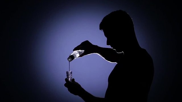 Man pouring vodka into a glass. Back light. SLow motion