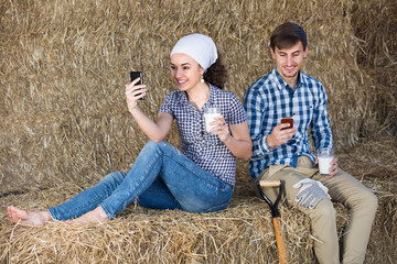 Young merry man and woman sitting together in the hay