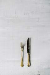 flat lay of golden fork and knife on grey concrete background. top view