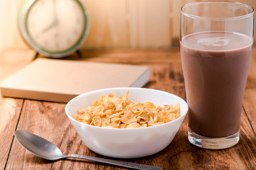 cornflakes cereal and chocolate milk on wood table