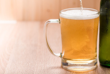 Beer pouring from top in bottle on wood table