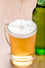 Beer pouring from top in bottle on wood table