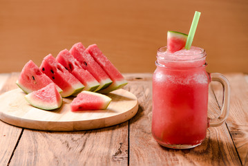Closeup watermelon juice in glass on wood table with with slices