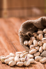 Roasted pistachios in sack on wood table,wood background
