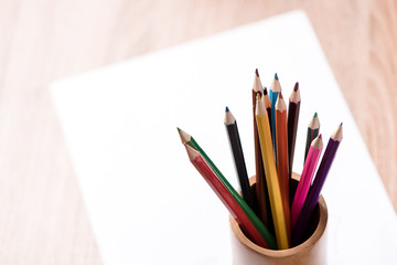 Naklejka premium coloured pencil and paper note on wood table