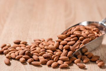almonds in metal scoop on wood table