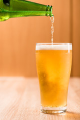 Beer pouring from top in bottle on wood table