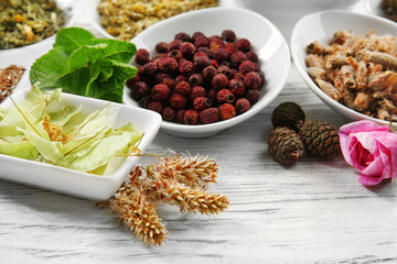 Natural flower and herb selection in ceramic bowls on wooden background