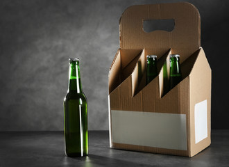 Bottle and paper beer package on table