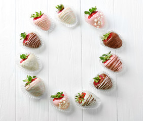 Circle of strawberries in chocolate on light wooden background