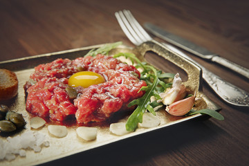 Steak tartar with chopped onion and pickles on a tray