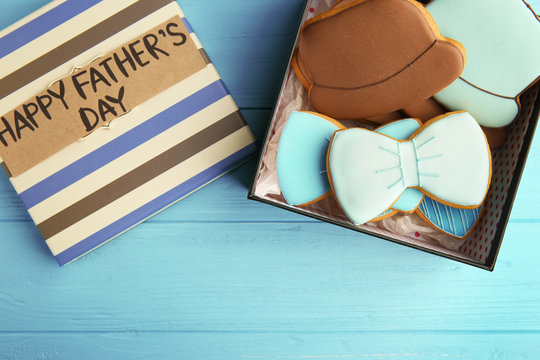 Happy Father's Day concept. Tasty cookies and gift box on blue wooden background