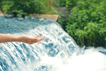 Female hand near water stream