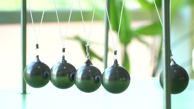  Slow motion,high speed camera. Newton's cradle: a pendulum with swinging metal spheres demonstrates conservation of momentum.