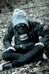 Tense child in gas mask sitting on ground