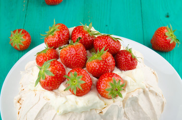 Pavlova cake with strawberry on rustic background.