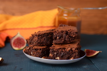 Brownie with walnuts, salted caramel, figs on a dark blue background with a yellow cloth