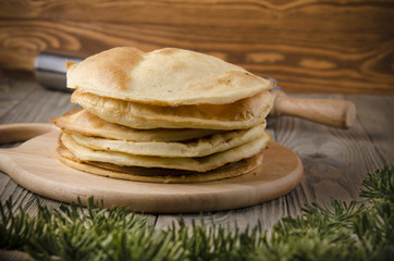 Cakes for the cake napoleon on a wooden background decorated with fir branches and rolling pin