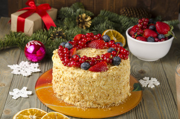 Napoleon cake with berries and fruit on wooden background. to celebrate Christmas or New Year decorated with fir branches, cones.