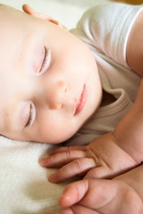 
An adorable little baby is sleeping on the bed in a white clothes