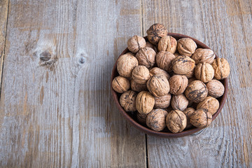 walnuts in a clay plate on a wooden background. top view