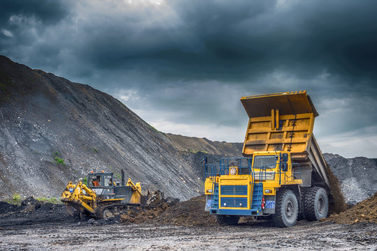 NOVOKUZNETSK, RUSSIA - JULY 26, 2016: Big yellow mining trucks and excavators at worksite

