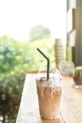 Photo sur Plexiglas Milk-shake Iced coffee (milk and caramel macchiato) in a plastic cup on the wood table.