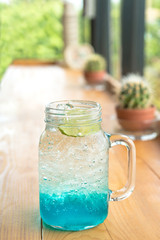 Blue Hawaiian lemon soda cocktail drinking (Blue curacao) in a glass cup on the wood table.