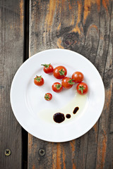 Cherry tomatoes with olive oil and balsamic vinegar on a white plate. Copy space