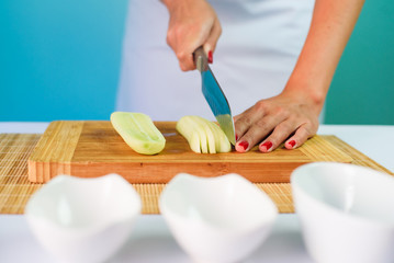 Close up picture of young lady's hands cutting cucumber