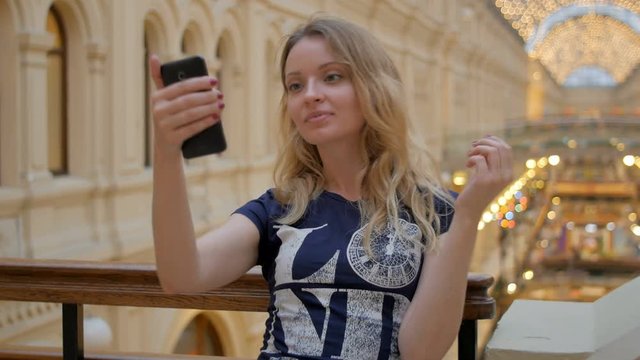 young slim blonde taking photo by smartphone in shopping mall
