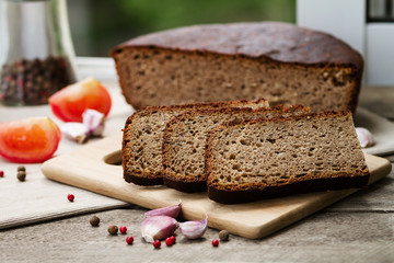 Rye bread. Bread on a wooden table, tomatoes and garlic
