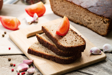 Rye bread. Bread on a wooden table, tomatoes and garlic