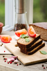 Rye bread. Bread on a wooden table, tomatoes and garlic